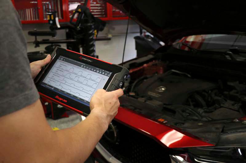 Technician using diagnostic scanner on vehicle